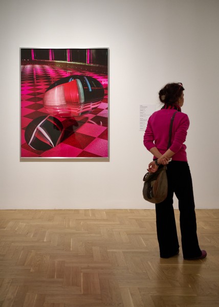 zdjęcie w przestrzeni wystawy, rozmazana postać pochylająca się nad instalacją